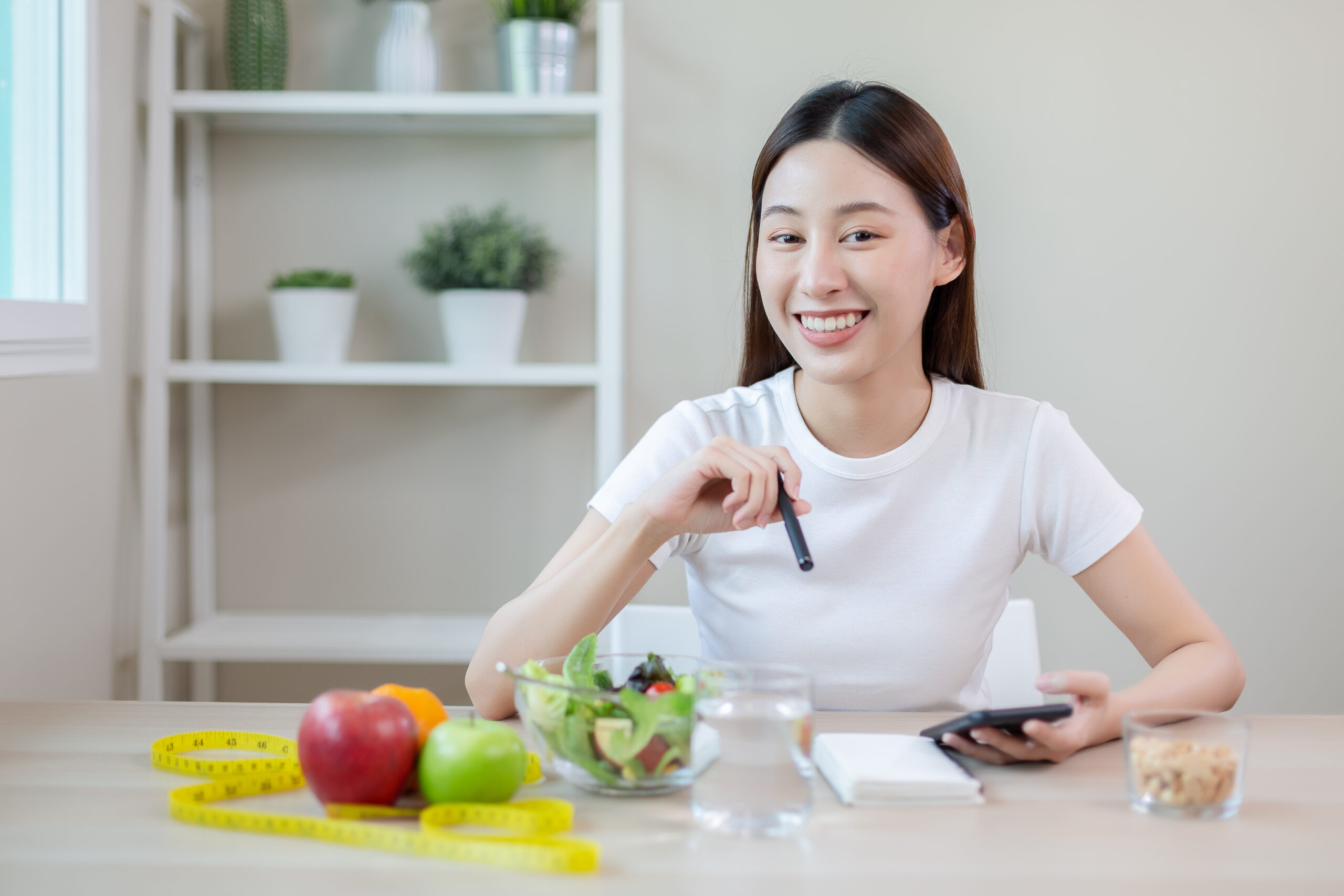 asian females using smartphones and taking notes eating healthy - Recuro Health | Making Advanced Healthcare Accessible™
